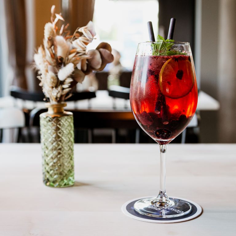 Fruchtiges Aperitif im Glas neben Blume